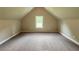 Finished attic space with carpet flooring, window and neutral paint - versatile bonus area at 125 Honey Creek Rd, Conyers, GA 30094