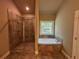 Bathroom featuring a glass-enclosed shower, a soaking tub under a window, and tile flooring at 125 Honey Creek Rd, Conyers, GA 30094