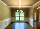 Elegant dining room with tray ceiling, wainscoting, modern chandelier, and a large window at 125 Honey Creek Rd, Conyers, GA 30094