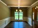 Formal dining room with a tray ceiling, wainscoting, hardwood floors, and a window overlooking the yard at 125 Honey Creek Rd, Conyers, GA 30094