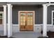 Inviting front entryway featuring double wooden doors with glass panels and classic white columns at 115 River Meadow Ln, Social Circle, GA 30025