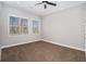 Bright bedroom with two windows offering outdoor views, ceiling fan and plush carpet flooring at 8955 Shalford Ct, Cumming, GA 30041