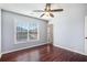 Bedroom with hardwood flooring, a ceiling fan, and a large window providing natural light at 8955 Shalford Ct, Cumming, GA 30041