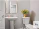 Neat powder room featuring a pedestal sink, modern toilet, elegant mirror, and fresh decor at 1579 Eastern Sunrise Ln, Decatur, GA 30034