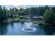 An aerial view displays a neighborhood amenity featuring a picturesque pond with a fountain and lush green landscaping at 7145 Hartsfield Pl, Suwanee, GA 30024