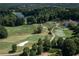 Aerial view of the golf course, lush greenery, and serene lake combine for a picturesque landscape at 7145 Hartsfield Pl, Suwanee, GA 30024