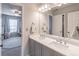 Bathroom featuring double sinks, neutral colors, and a doorway to a bright bedroom with a ceiling fan at 7145 Hartsfield Pl, Suwanee, GA 30024