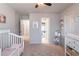 Bright Bedroom featuring a white crib, soft rug, and charming decor, creating a cozy space at 7145 Hartsfield Pl, Suwanee, GA 30024