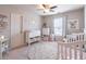 Adorable Bedroom featuring a crib, changing table, a white dresser, and a patterned rug at 7145 Hartsfield Pl, Suwanee, GA 30024