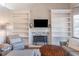 Inviting living room featuring built-in shelving and a cozy fireplace with decorative stone surround at 7145 Hartsfield Pl, Suwanee, GA 30024