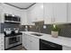 Close-up of modern kitchen featuring stainless steel appliances, black backsplash, and white countertops at 9 Market Square Nw Pl, Atlanta, GA 30318