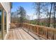 The outdoor back deck has wood flooring and railing, offering a serene view of surrounding trees at 514 Eagles Pt, Fairburn, GA 30213