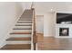 Staircase with wooden stairs and white risers leading to a living room with a fireplace at 514 Eagles Pt, Fairburn, GA 30213