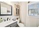 Cozy bathroom features gray vanity with white countertop, a decorative mirror, and natural light from the window at 2883 Misty Rock Cv, Dacula, GA 30019