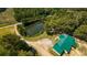Scenic aerial shot showcasing a property with a green-roofed house next to a pond nestled in lush greenery at 9180 Shiloh Dr, Villa Rica, GA 30180