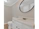 This cozy bathroom features a white sink, toilet, and vanity with a stylish black framed circular mirror at 9180 Shiloh Dr, Villa Rica, GA 30180