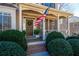 Inviting front porch features classic columns, an American flag, and manicured shrubs at 5383 Fawn Meadow Ln, Powder Springs, GA 30127