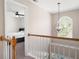 Hallway with wood railing features a modern chandelier with a view to a bright bedroom at 5383 Fawn Meadow Ln, Powder Springs, GA 30127