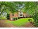 A lush green lawn wraps around the rear of the brick home, complete with a wooden deck area for outdoor enjoyment at 828 Guinevere Sw Way, Lilburn, GA 30047