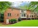 View of a two-story brick home featuring a spacious wooden deck and well-maintained lawn surrounded by mature trees at 828 Guinevere Sw Way, Lilburn, GA 30047