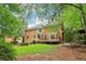 Backyard view of home with a deck, grassy lawn, and wooded area at 828 Guinevere Sw Way, Lilburn, GA 30047