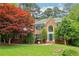 Charming brick home featuring a manicured lawn, mature trees, and inviting blue door at 828 Guinevere Sw Way, Lilburn, GA 30047