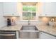 Close-up of a kitchen sink with granite countertop and white cabinets with a window above the sink at 1438 Ridgeland Sw Ct, Lilburn, GA 30047