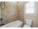 Bathroom with tiled shower and tub and a white toilet under a window bringing in natural light at 1655 Dawn Dr, Suwanee, GA 30024