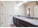 Bathroom featuring dual sinks with granite counters and dark wood cabinets, complemented by neutral walls and white doors at 1655 Dawn Dr, Suwanee, GA 30024