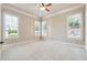 Spacious, light-filled bedroom featuring plush carpet, ceiling fan, and multiple windows at 1655 Dawn Dr, Suwanee, GA 30024
