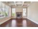 Living room featuring a stone fireplace, hardwood floors, coffered ceiling, and large windows at 1655 Dawn Dr, Suwanee, GA 30024