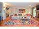 Open-concept living room with a decorative fireplace, plush sofa, large colorful rug, and hardwood floors at 5500 Georgetown Sw Trce, Lilburn, GA 30047