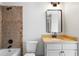Bathroom featuring brown tile surround, black fixtures, decorative vanity, and dark framed mirror at 111 Carter Ln, Canton, GA 30115