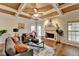 Inviting living room features a coffered ceiling, fireplace, large windows, and hardwood floors at 1915 Turtle Creek Way, Lawrenceville, GA 30043