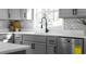 Close-up of a kitchen sink area with gray cabinets, stainless steel dishwasher, and herring bone tile backsplash at 513 S Malton Ct, Stone Mountain, GA 30083