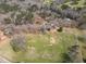 Aerial view showcasing a vast, grassy property with mature trees, a home, and outbuildings at 75 Price Dr, Locust Grove, GA 30248