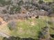 Aerial view showcasing a vast, grassy property with mature trees, a home, and outbuildings at 75 Price Dr, Locust Grove, GA 30248