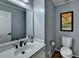 Bathroom features a vanity with white sink, brushed bronze faucet, art, and a toilet on a hardwood floor at 2030 Habersham Trce, Cumming, GA 30041