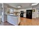Bright kitchen with white cabinets, black appliances, hardwood floors, and breakfast bar at 2030 Habersham Trce, Cumming, GA 30041