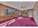 Bright sun room with wood paneling, red carpet, ceiling fan, and multiple windows with natural light at 133 Hickory Trl, Cumming, GA 30040