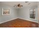A simple bedroom space with a ceiling fan, wood floors, and two windows for natural light at 2870 Carla Nw Dr, Kennesaw, GA 30144