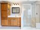 Well-lit bathroom featuring a glass-enclosed shower and a vanity with warm wood cabinets at 2536 Kachina Trl, Dacula, GA 30019