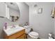 Bathroom with grey walls, round mirror, oak vanity, and white toilet at 4453 Abingdon Dr, Stone Mountain, GA 30083