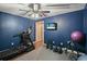 Home gym with sleek black treadmill, rubber floors, mounted television, and blue accent walls at 1090 Compton Way, Suwanee, GA 30024