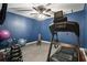 Home gym with sleek black treadmill, rubber floors, a ceiling fan, and blue accent walls at 1090 Compton Way, Suwanee, GA 30024
