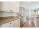 Well-lit kitchen featuring white cabinetry, granite countertops, stainless steel appliances, and hardwood flooring at 1090 Compton Way, Suwanee, GA 30024