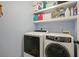 Functional laundry room with modern side-by-side washer and dryer and storage shelves at 1090 Compton Way, Suwanee, GA 30024