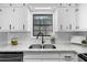 Kitchen with a stainless steel sink, granite counters, white cabinetry, and a subway tile backsplash at 2735 Varlet Ct, Snellville, GA 30039