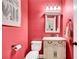 Charming half bathroom with stylish vanity, mirror, lighting, and vibrant coral-colored walls at 2138 Jockey Hollow Nw Dr, Kennesaw, GA 30152