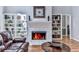 Cozy fireplace with white tile surround, flanked by built-in bookshelves, with hardwood floors and an adjacent doorway at 5090 Eubanks Rd, Woodstock, GA 30188